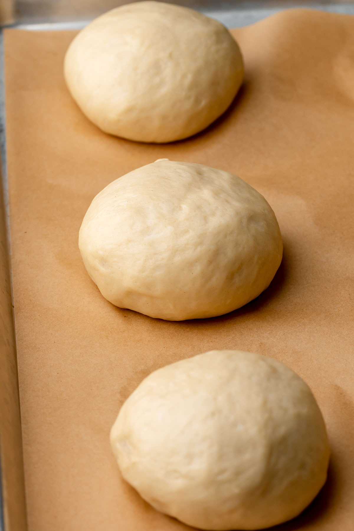 Puffy, risen balls of dough on a baking sheet.