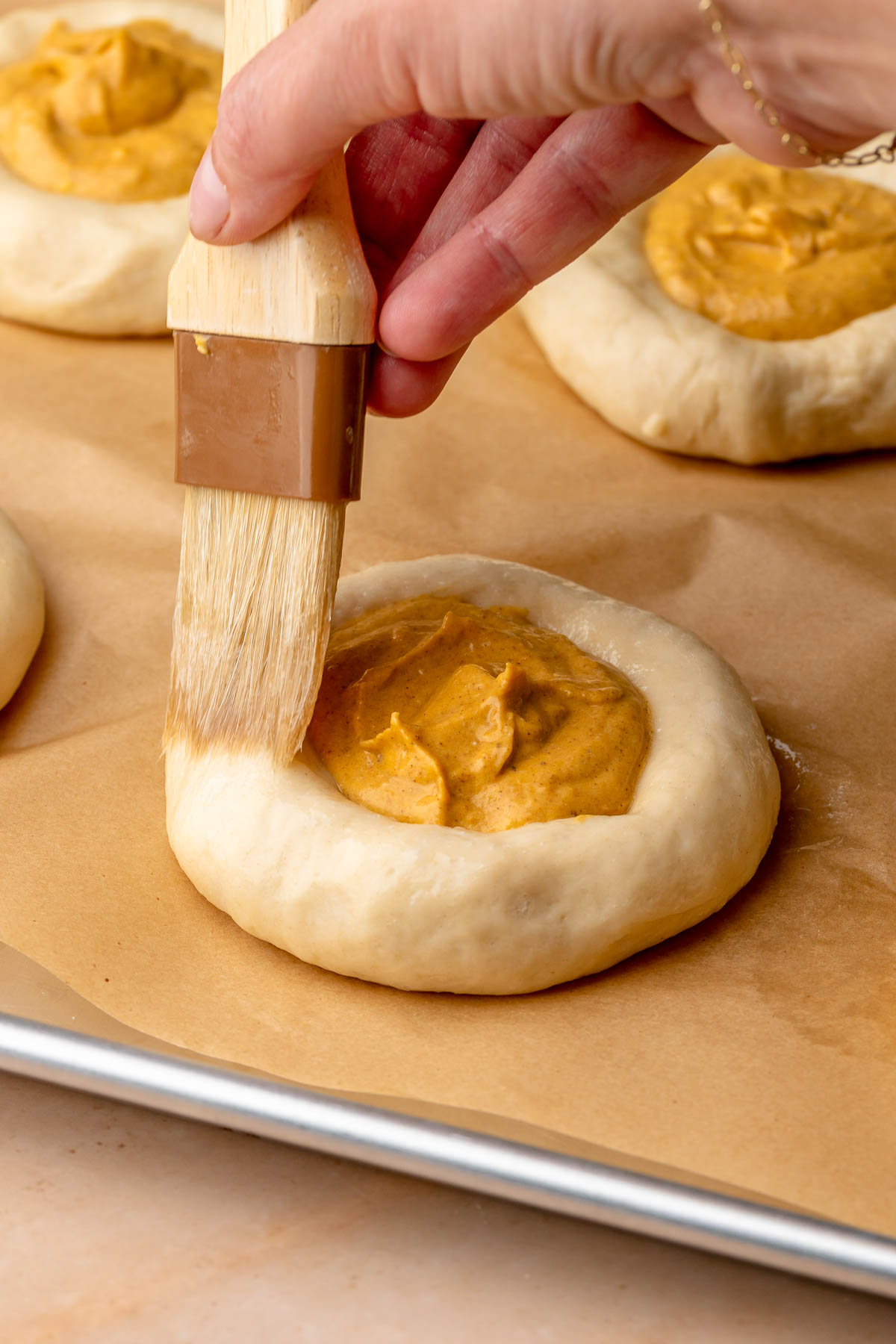 A pastry brush adds egg wash to the sides of the filled brioche buns.