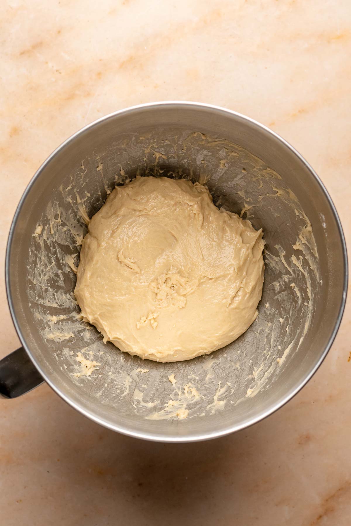 A ball of brioche dough in a mixing bowl.