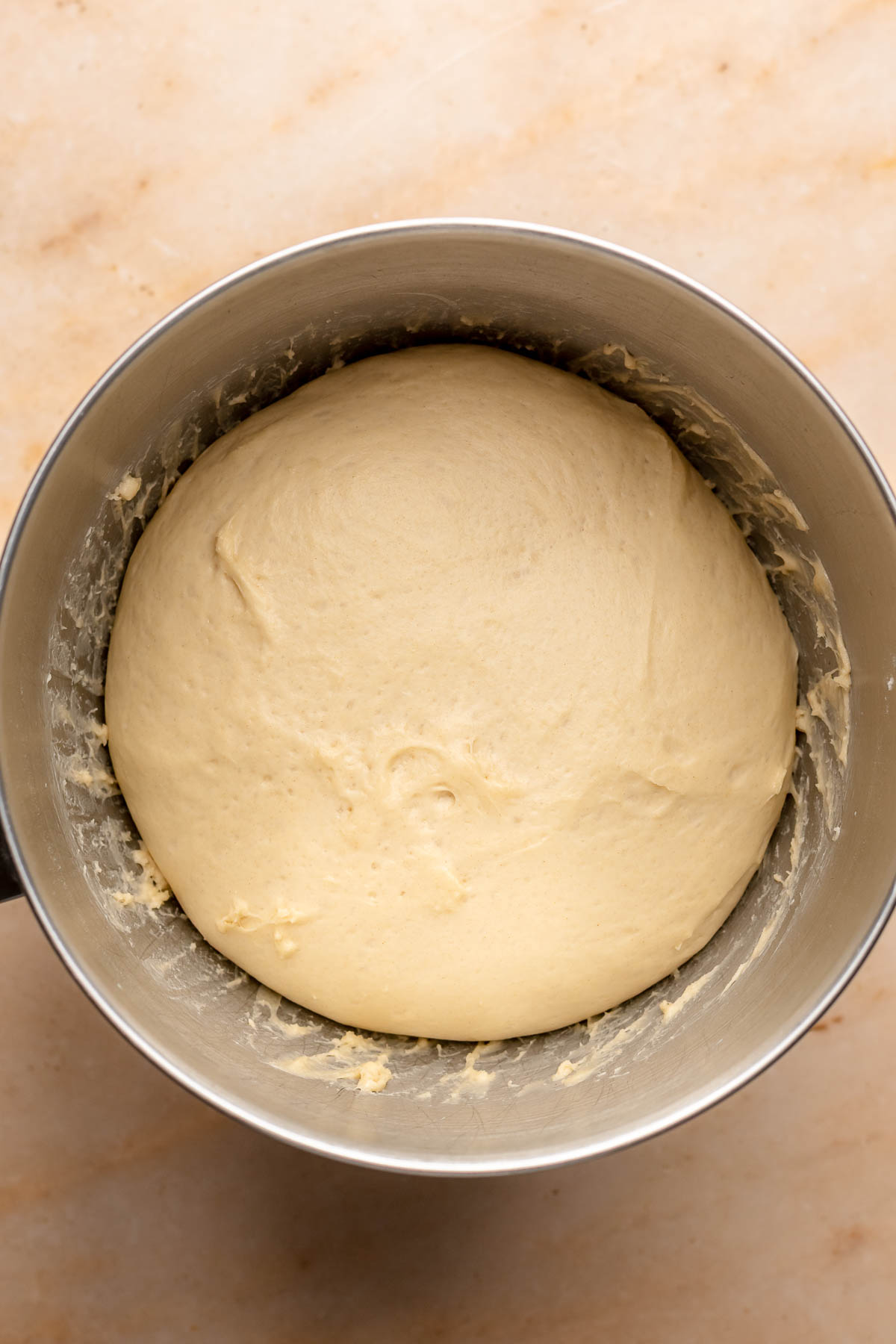 Puffy, risen brioche dough in a mixing bowl.