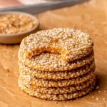 A stack of sweet potato sesame cookies on parchment paper. The top one has a bite removed.