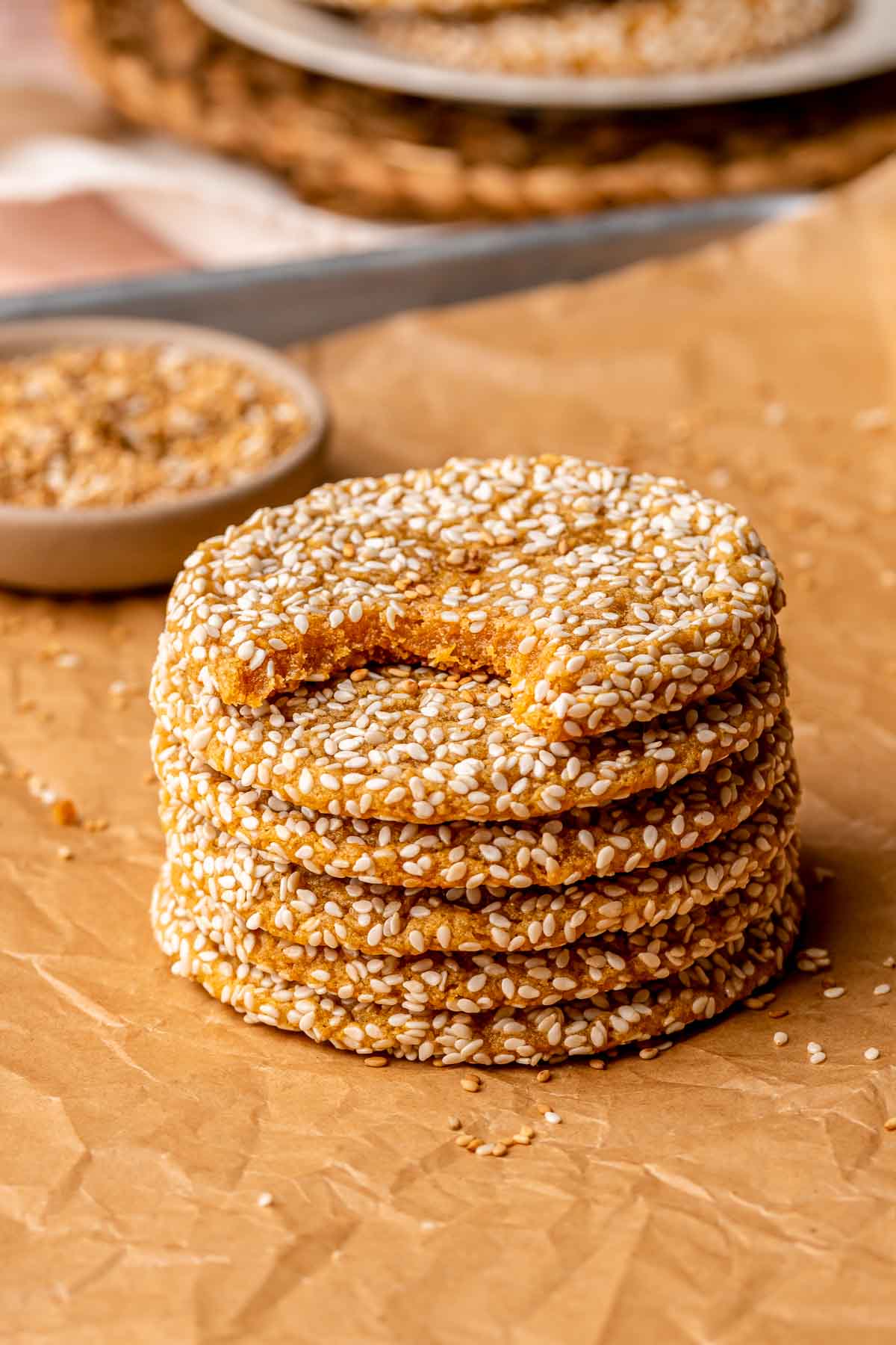 A stack of sweet potato sesame cookies on parchment paper. The top one has a bite removed.