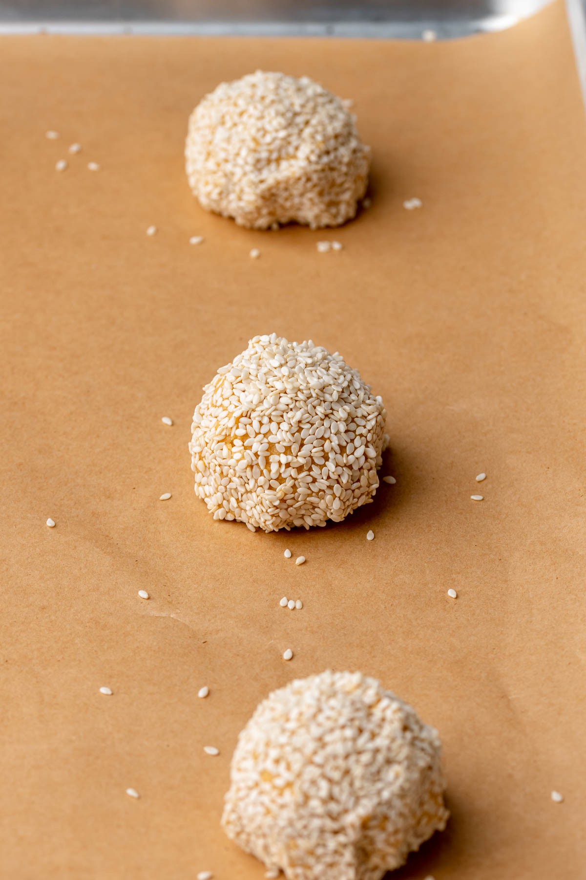 Sweet potato cookie dough balls rolled in sesame seeds on a sheet pan.