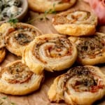 A stack of puff pastry pinwheels on parchment paper.