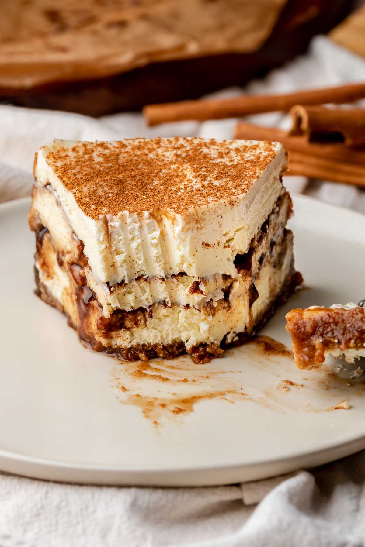 Bites removed from the tip of a slice of cinnamon roll cheesecake.