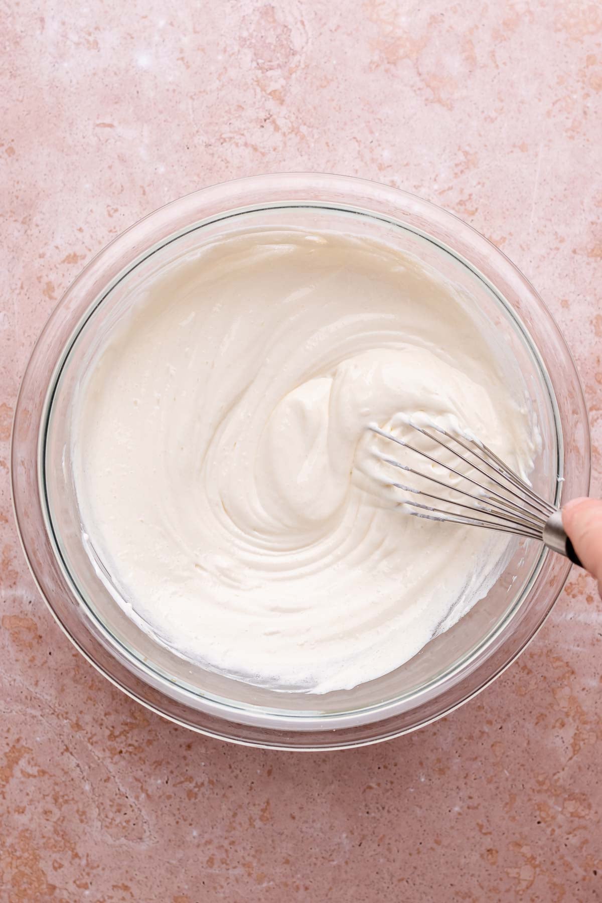 A whisk mixes sour cream topping in a mixing bowl.