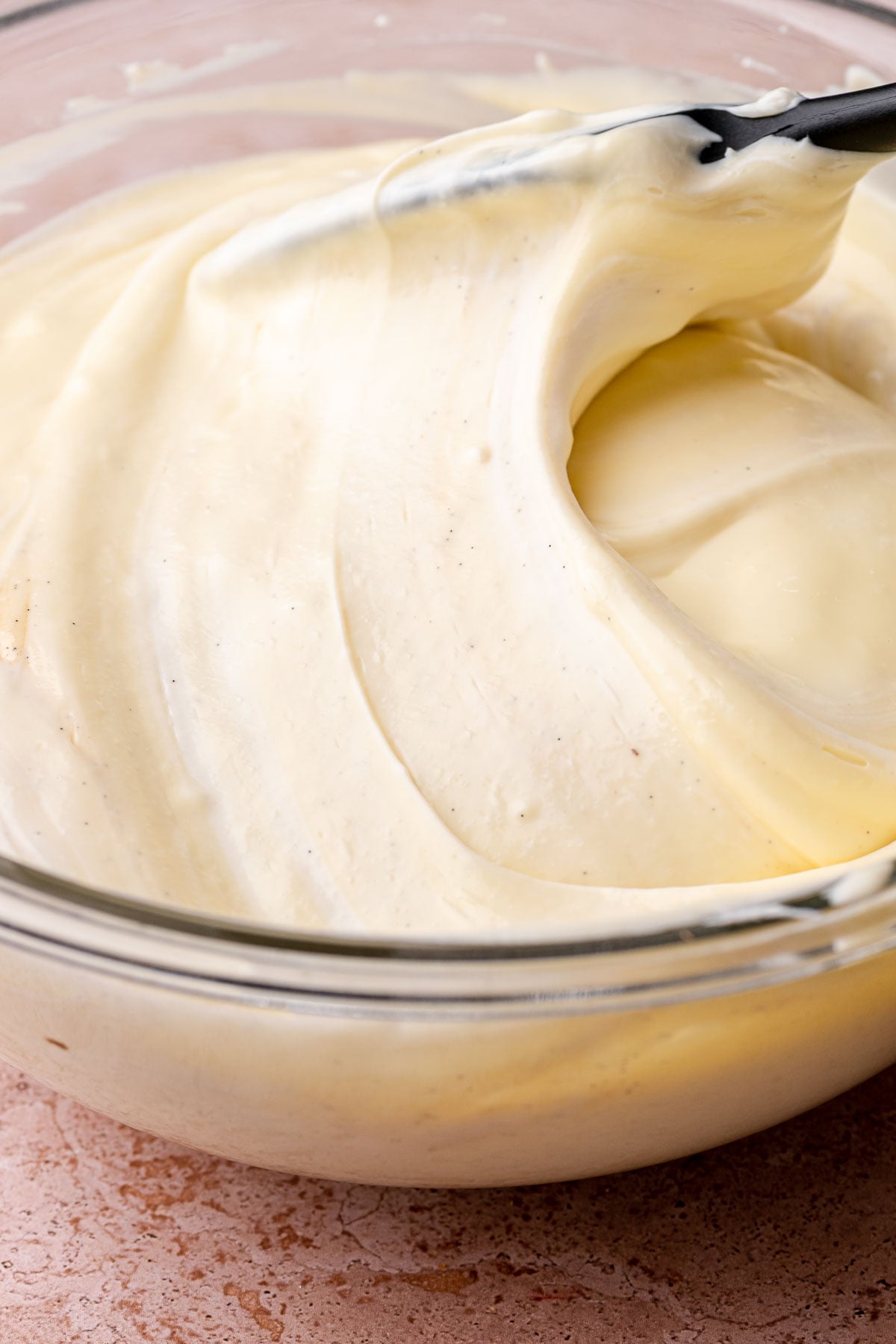 A spatula folds cheesecake batter in a bowl.