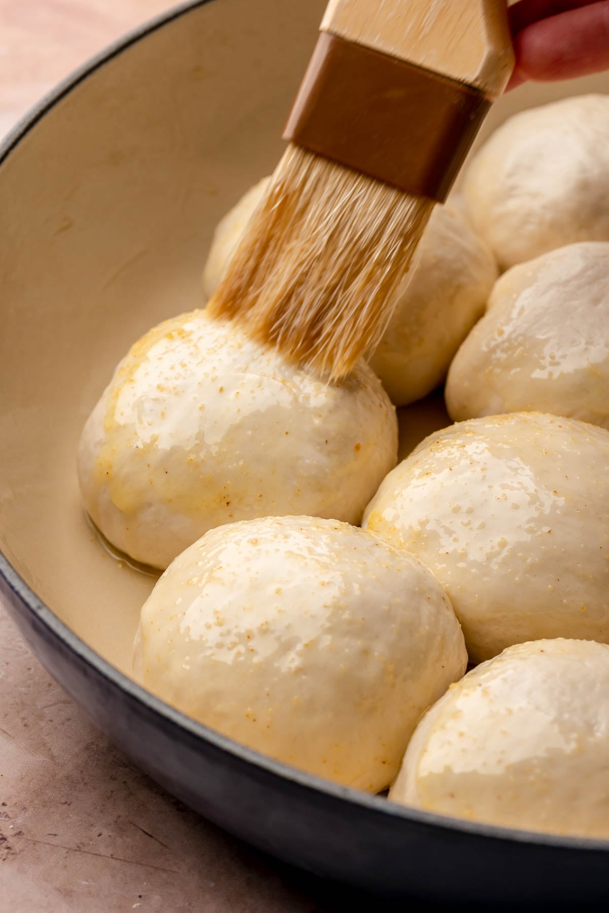 A pastry brush swipes garlic butter onto the pre-baked pizza bites.