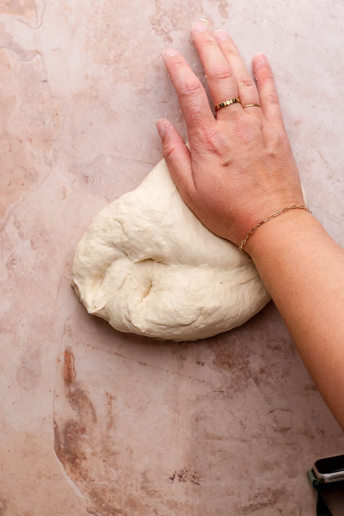 A hand kneads dough on the counter.