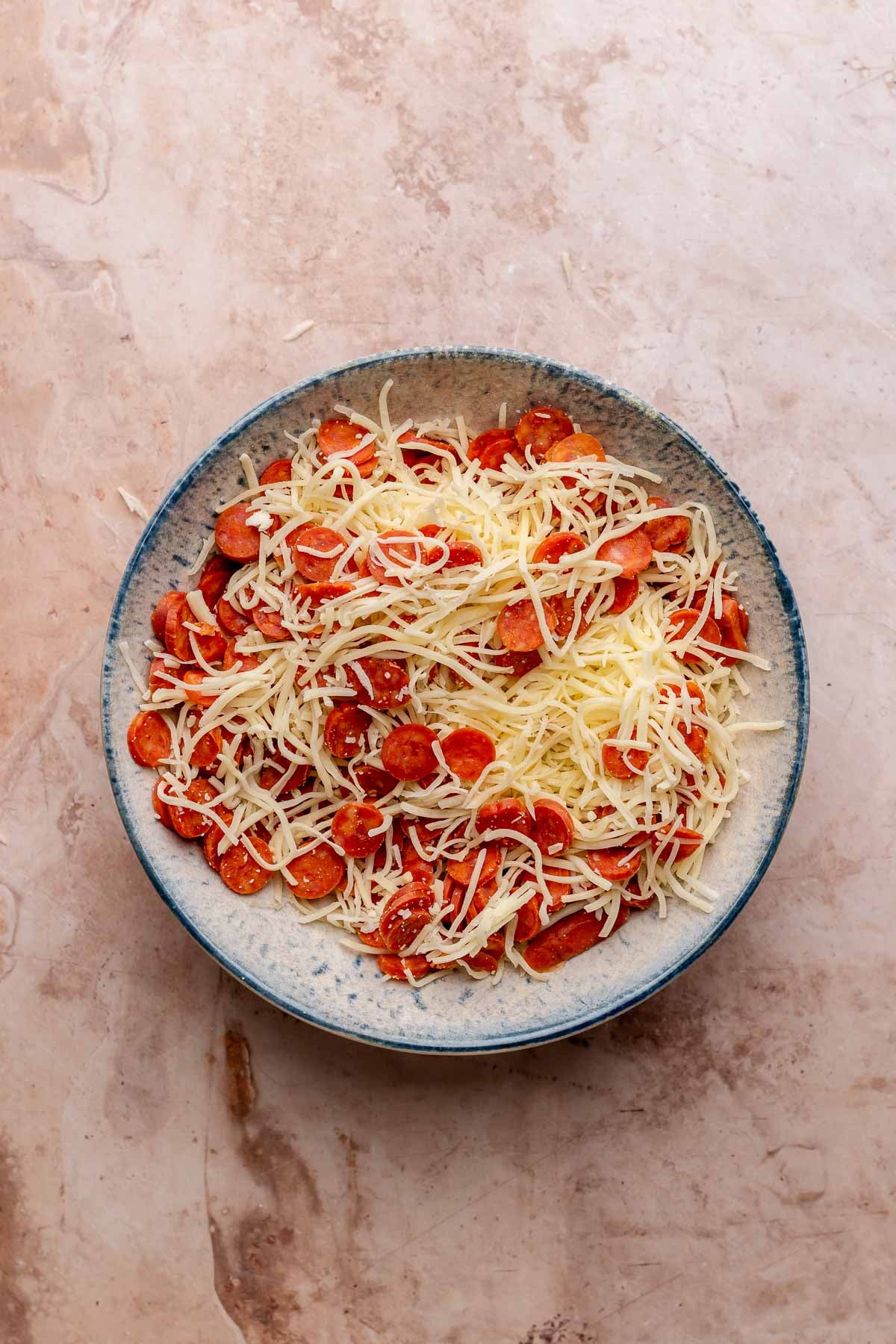Shredded mozzarella and pepperoni mix in a bowl.