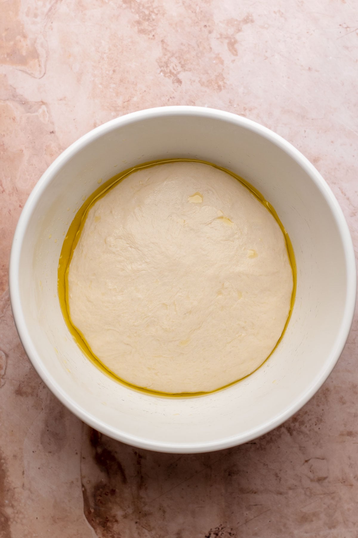 Risen pizza dough in a bowl.