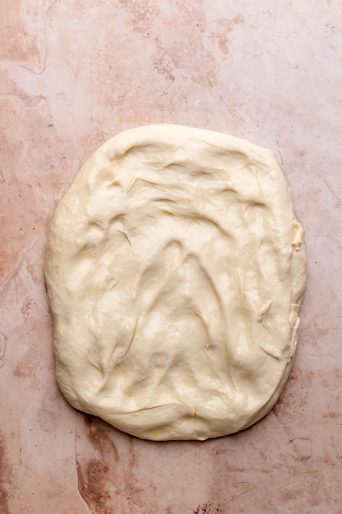Rectangle of pizza dough on a counter.