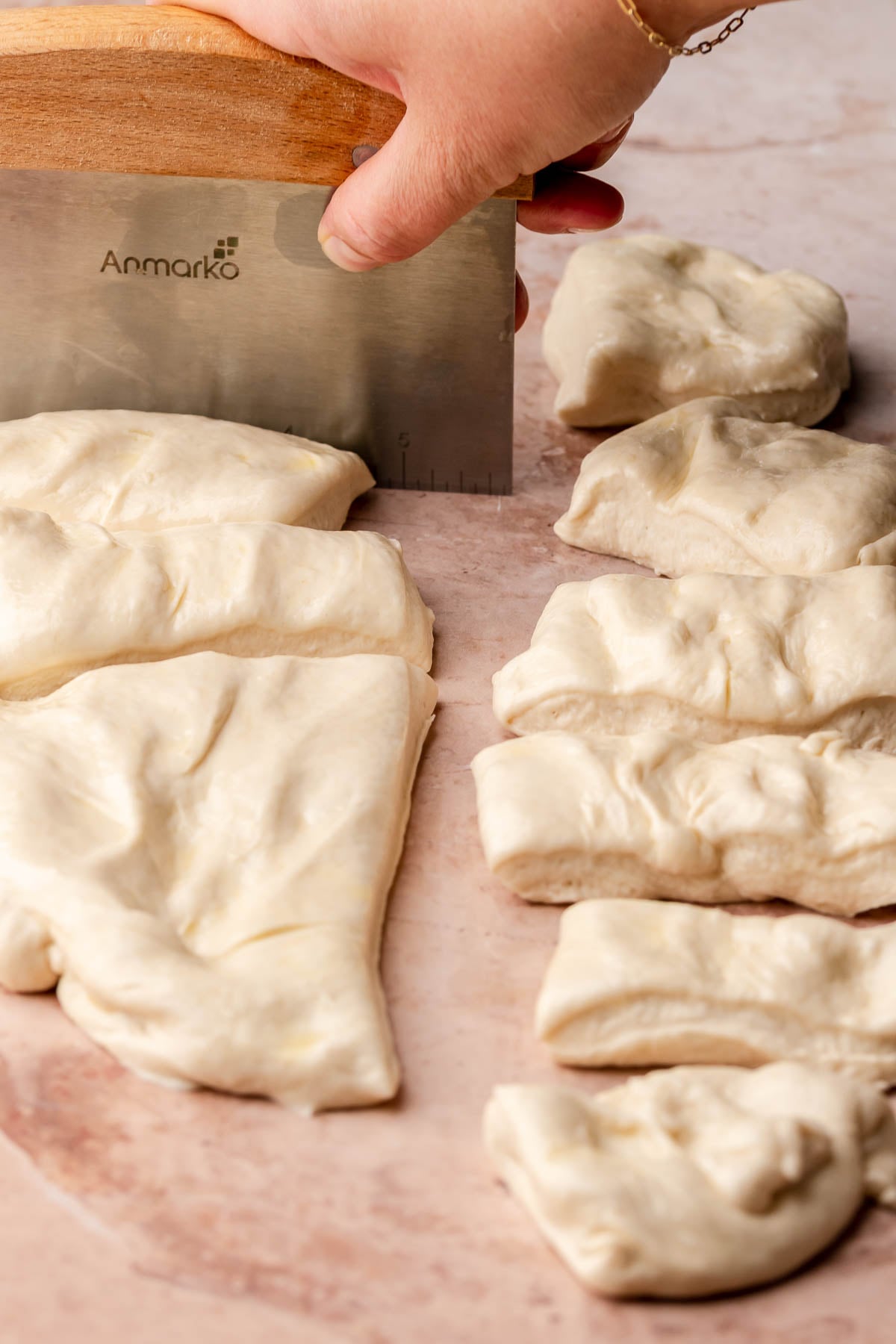 A bench scraper cuts pizza dough into even pieces.