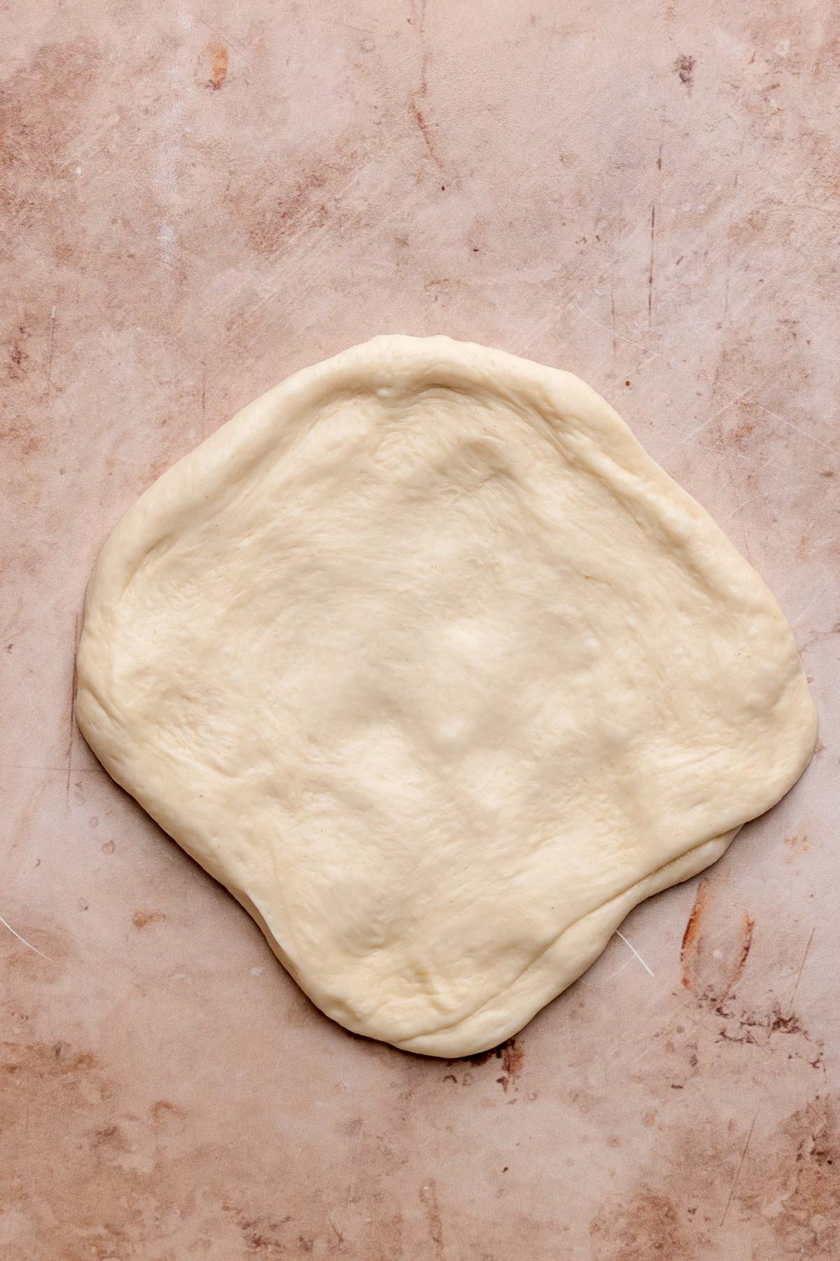 A flat round of pizza dough on the counter.