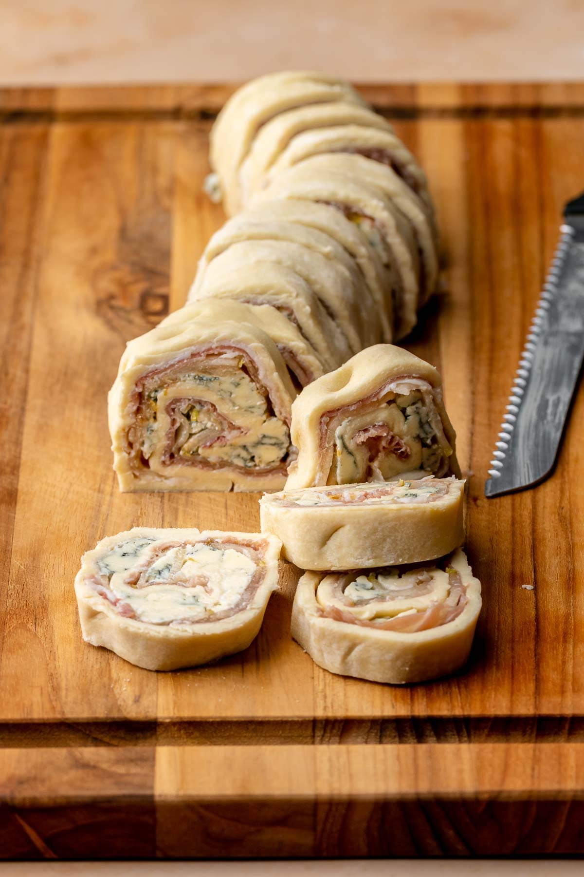 Slices of puff pastry pinwheels on a cutting board. A serrated knife sits on the side.