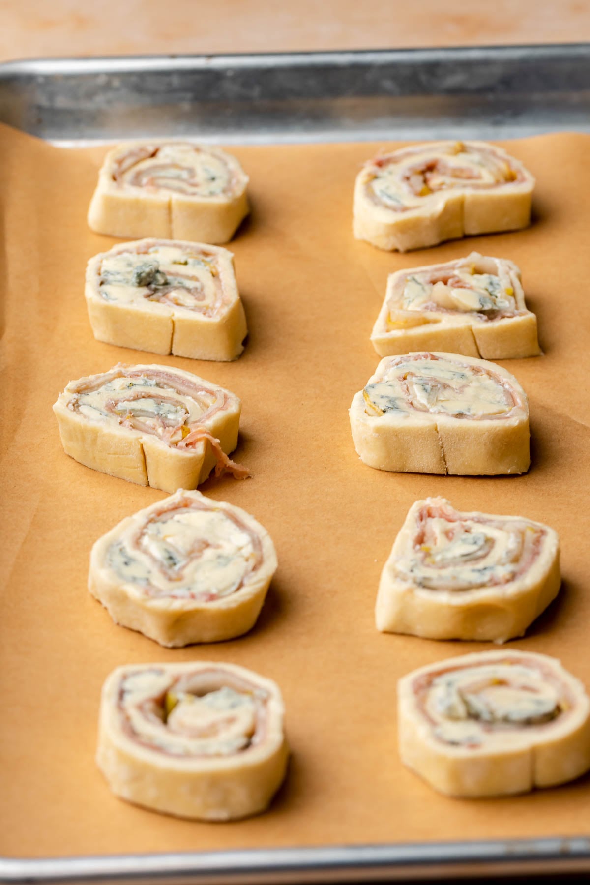 Slices of puff pastry pinwheels on a baking sheet.